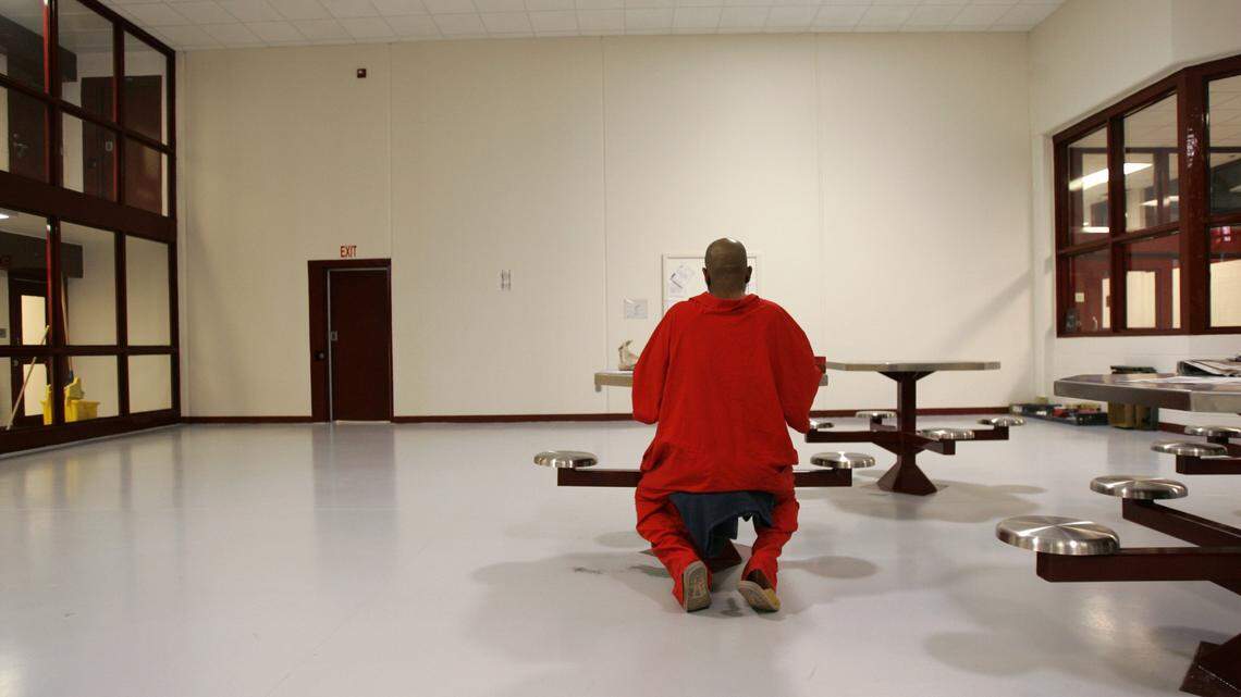 An inmate on death row at Central Prison in Raleigh works on a letter in a common area in one of the four pods on death row in 2004. Inmates on death row wear red to signify they are on death row.