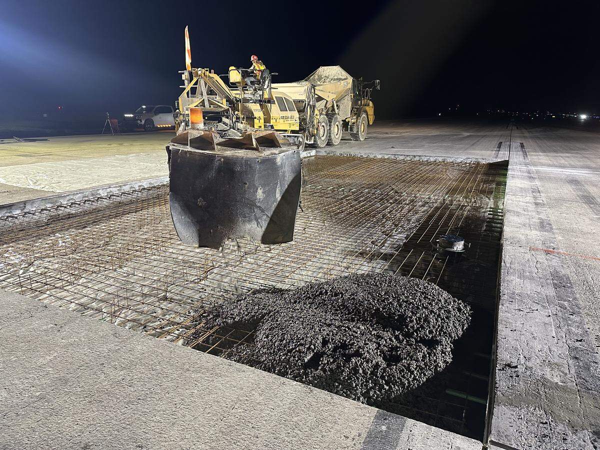 Wet concrete flows off a conveyor into the 25-by-50-foot hole in the main runway at Raleigh-Durham International Airport at about 10:20 p.m. on Oct. 20, 2025.