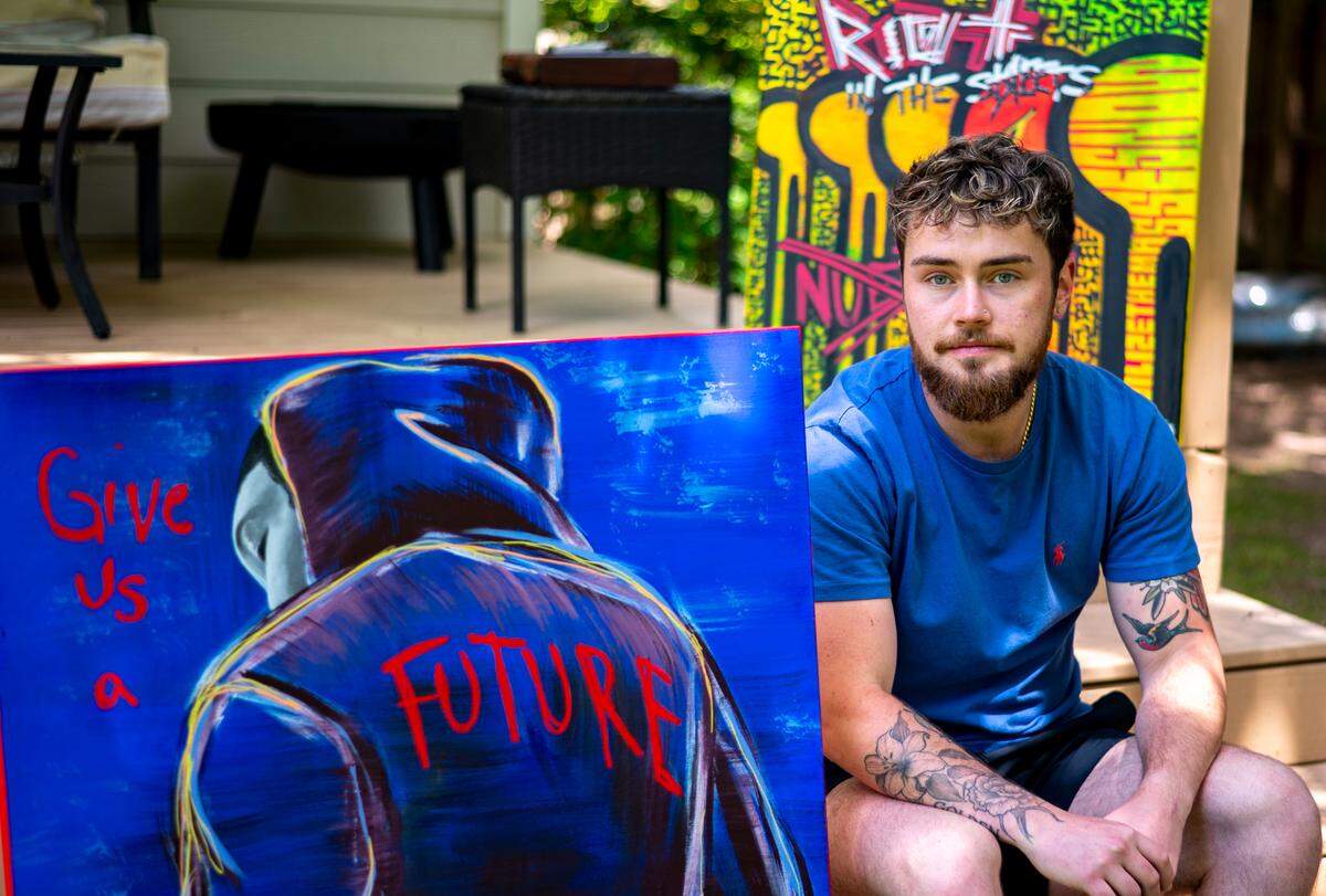 Zan poses for a portrait with paintings he made advocating for marginalized groups. Since he was a kid he gravitated towards painting, one of his earliest memories being in kindergarten trying to recreate Van Gogh’s “Starry Night.” Now his work sends messages of resistance.