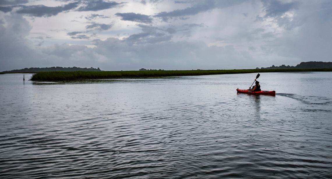 A kayaker paddles alone during low tide in an undeveloped section of Murrells Inlet that is protected by Huntington Beach State Park.