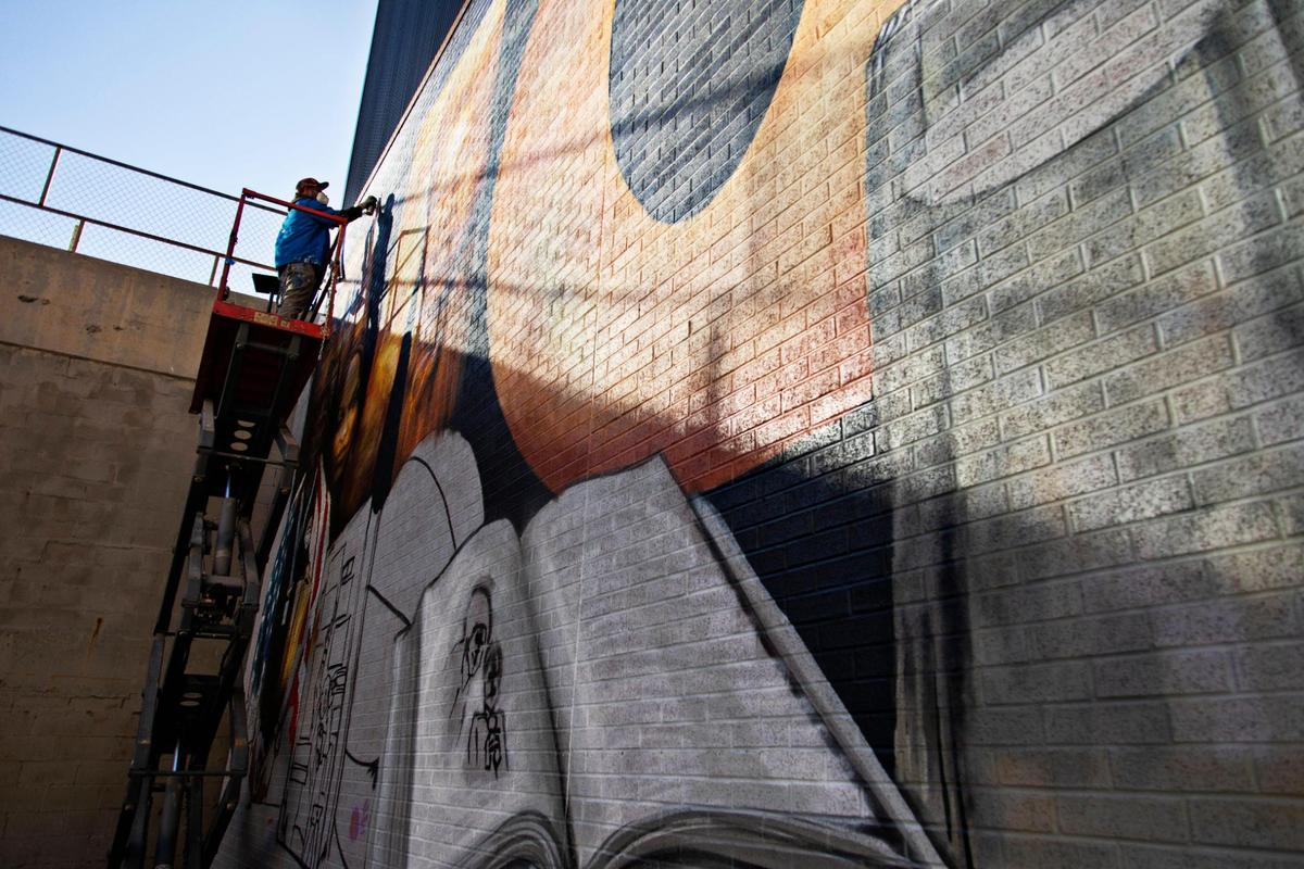 Artist Sean Kernick works on the finishing touches of his mural to honor NCCU coach LaVelle Moton on Salibury St. in downtown Raleigh on Tuesday, Nov. 23. 2021.