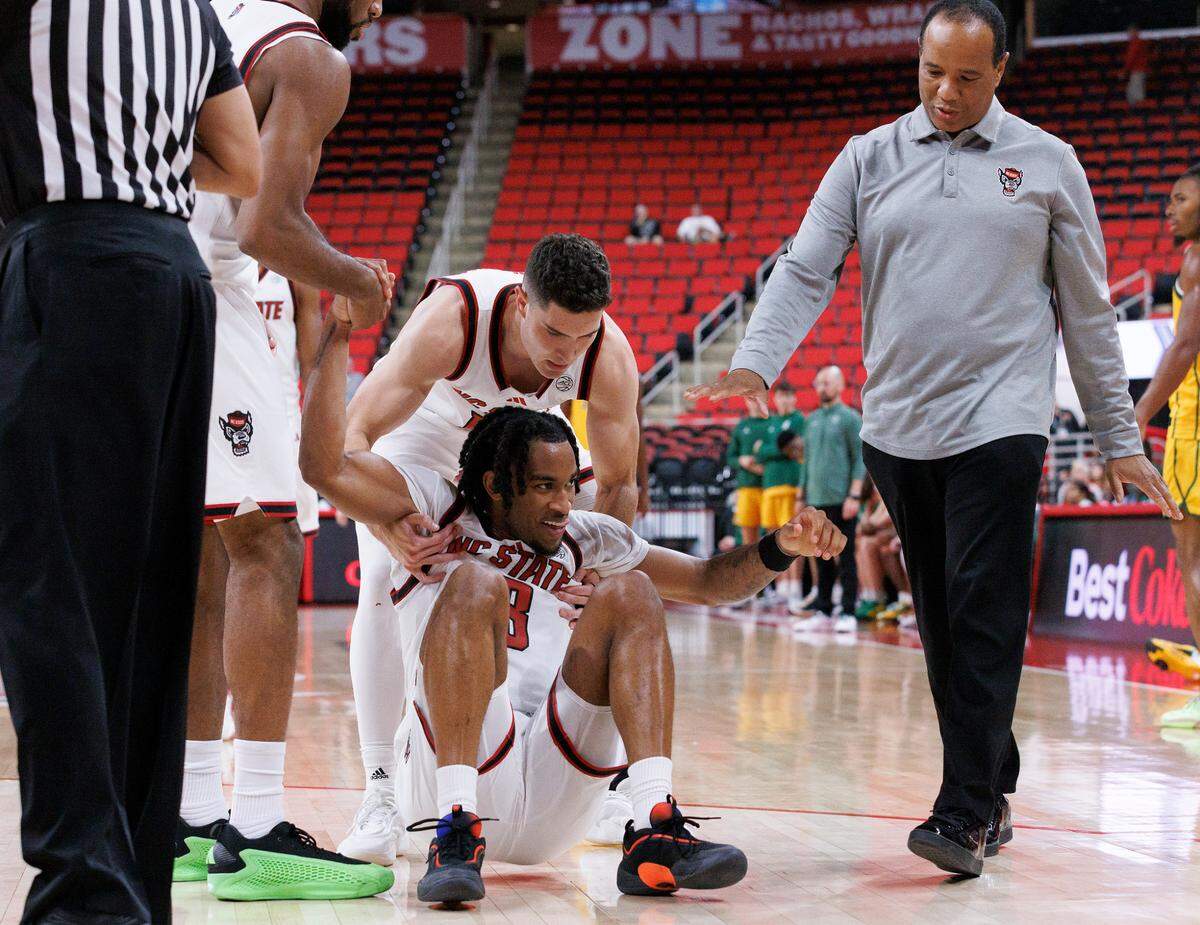 Teammates and N.C. State head coach Kevin Keatts help up Jayden Taylor during the second half of the Wolfpack’s 79-75 exhibition win over Lees-McRae on Wednesday, Oct. 30, 2024, at the Lenovo Center.