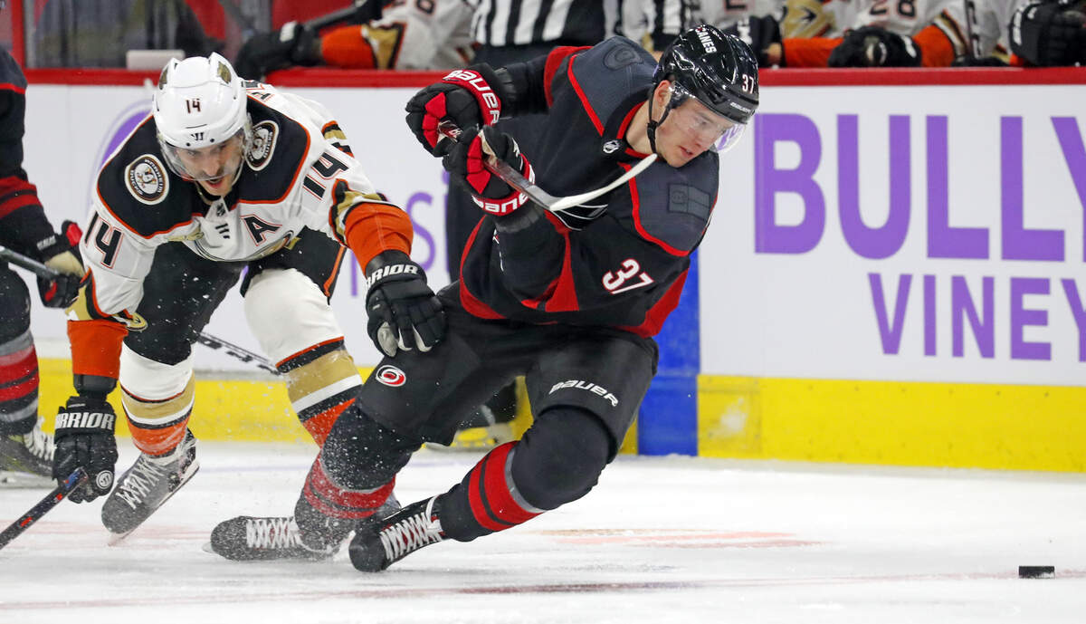 Carolina Hurricanes’ Andrei Svechnikov (37) eyes the puck after colliding with Anaheim Ducks’ Adam Henrique (14) during the first period of an NHL hockey game, Friday, Nov. 30, 2018