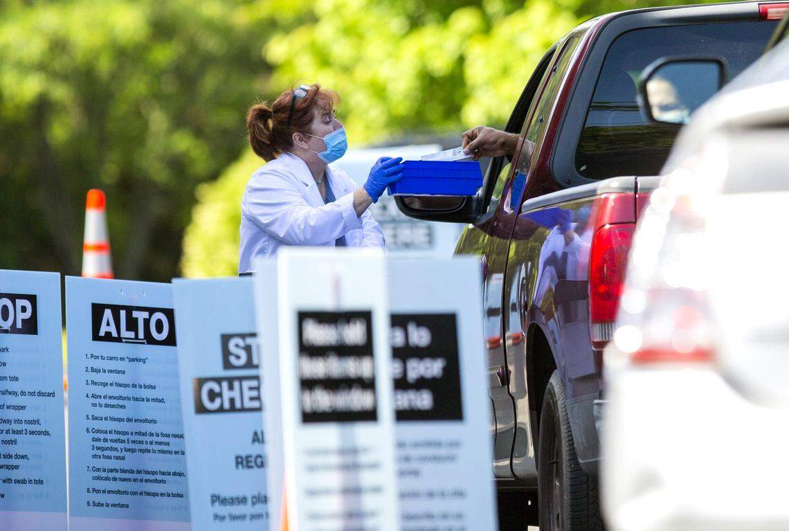 A completed coronavirus test is transferred through the car window at a free drive-through testing site administered by Walgreens across the street from their Guess Road location in Durham, N.C., on Friday, May 15, 2020.