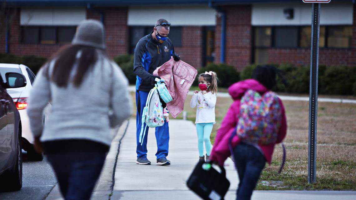 Princeton Elementary School PE teacher Justin Willoughby, center left, helps a student with her coat and backpack Monday morning, Feb. 1, 2021, in Princeton, NC. Despite lobbying from some teachers to stay with remote instruction, Johnston students across all grade levels showed up Monday for their first day of in-person classes since Dec. 14.