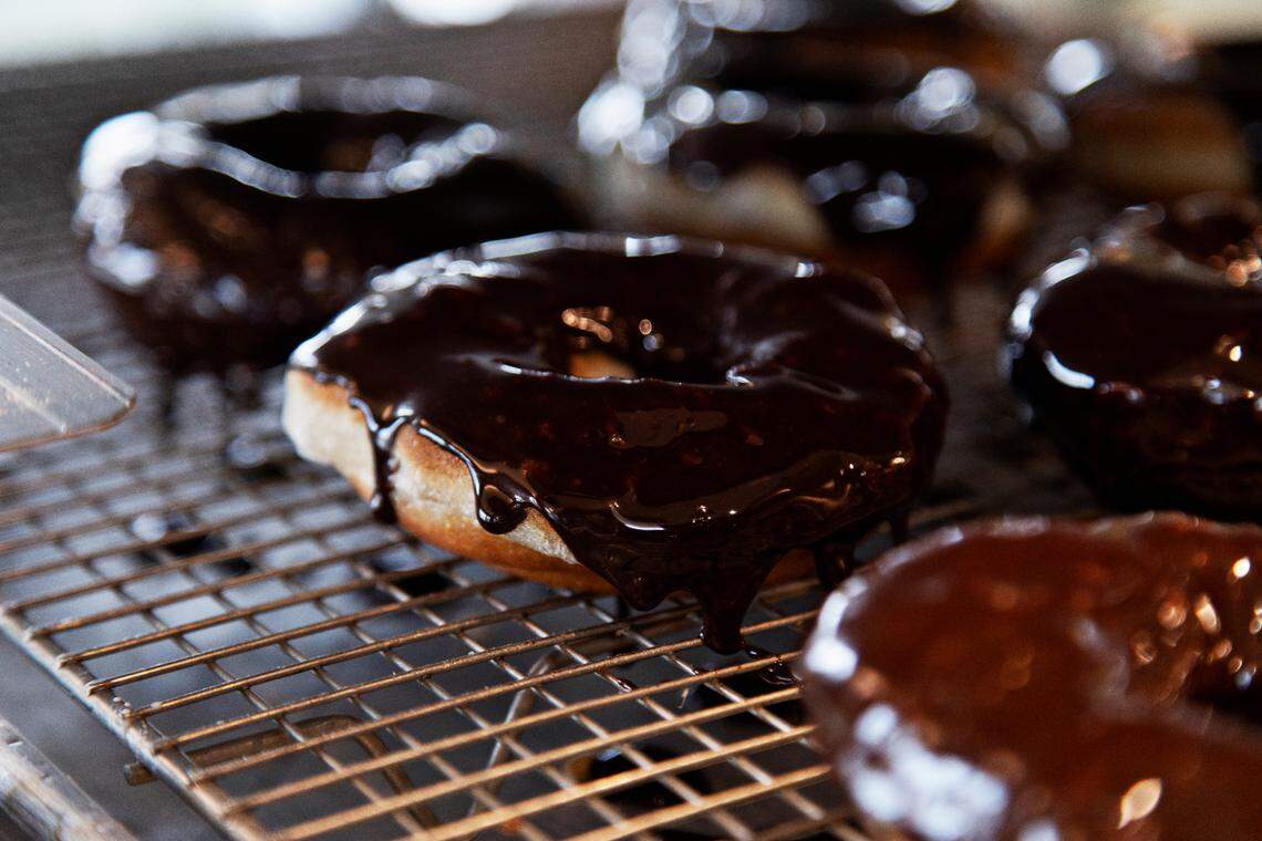 Freshly fried donuts are topped with a chocolate glaze on Friday, March 18, 2022, at the new Raleigh bakery, Bright Spot Donuts, which will open soon in the Five Points Neighborhood.