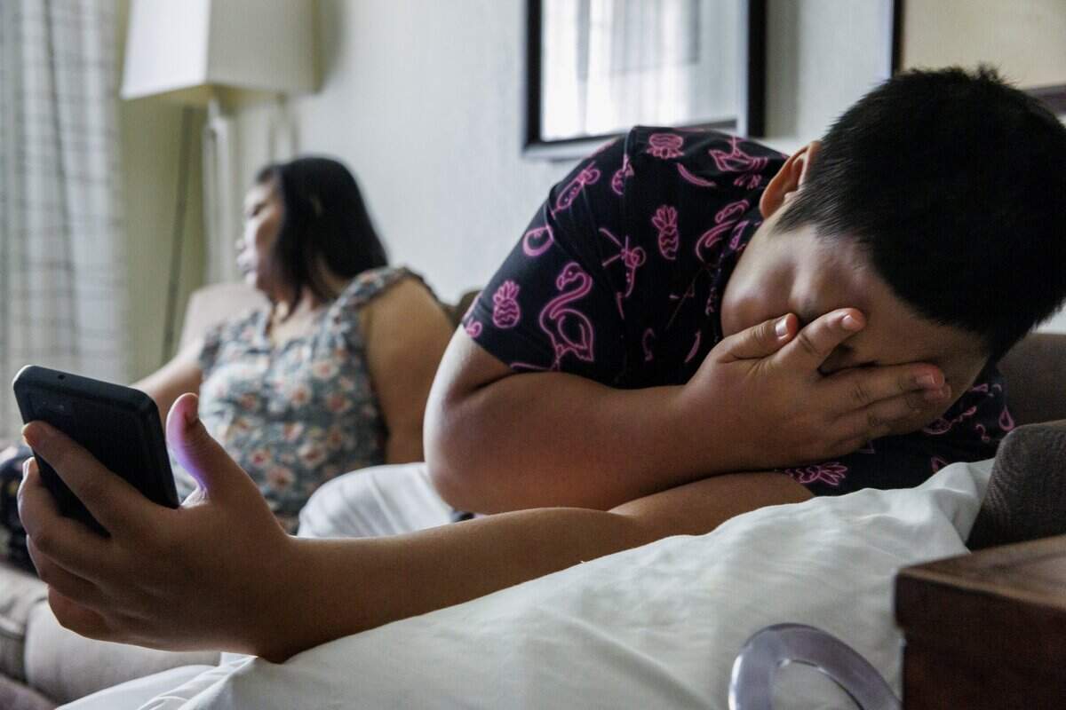 Kyawwin Hling, Mu La Pur’s son, wipes his hand across his face while resting on the sofa with his mother inside the hotel room his family current lives at on Tuesday, June 30, 2026, in Chapel Hill, North Carolina.