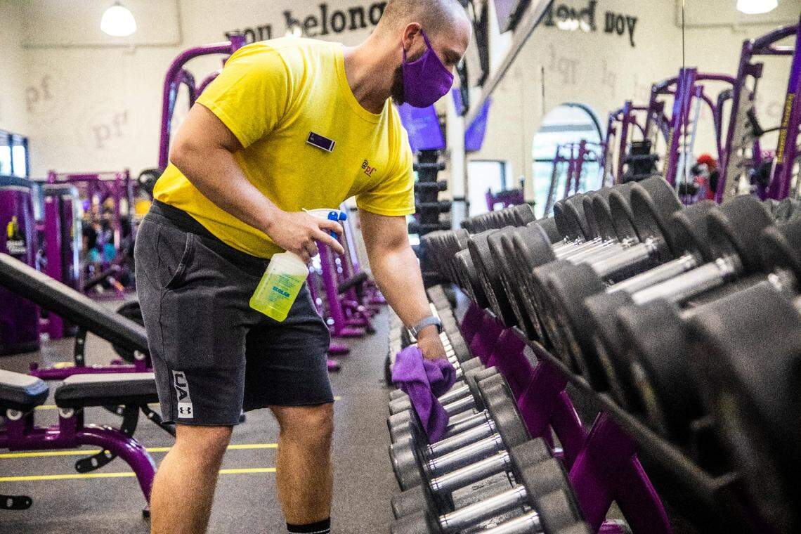 Trainer Kyle Dexter wipes down dumbells at a Planet Fitness gym in North Raleigh. Planet Fitness is reopening some gyms in North Carolina this week, despite a coronavirus executive order that keeps gyms closed.
