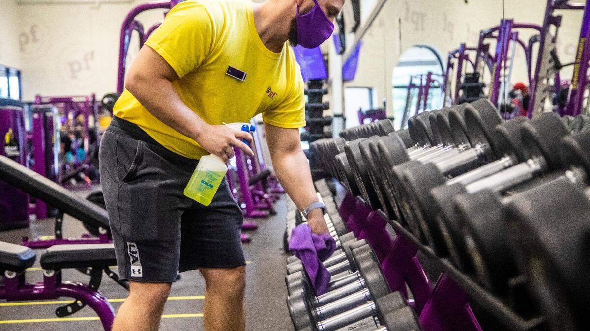Trainer Kyle Dexter wipes down dumbells at a Planet Fitness gym in North Raleigh. Planet Fitness is reopening some gyms in North Carolina this week, despite a coronavirus executive order that keeps gyms closed.