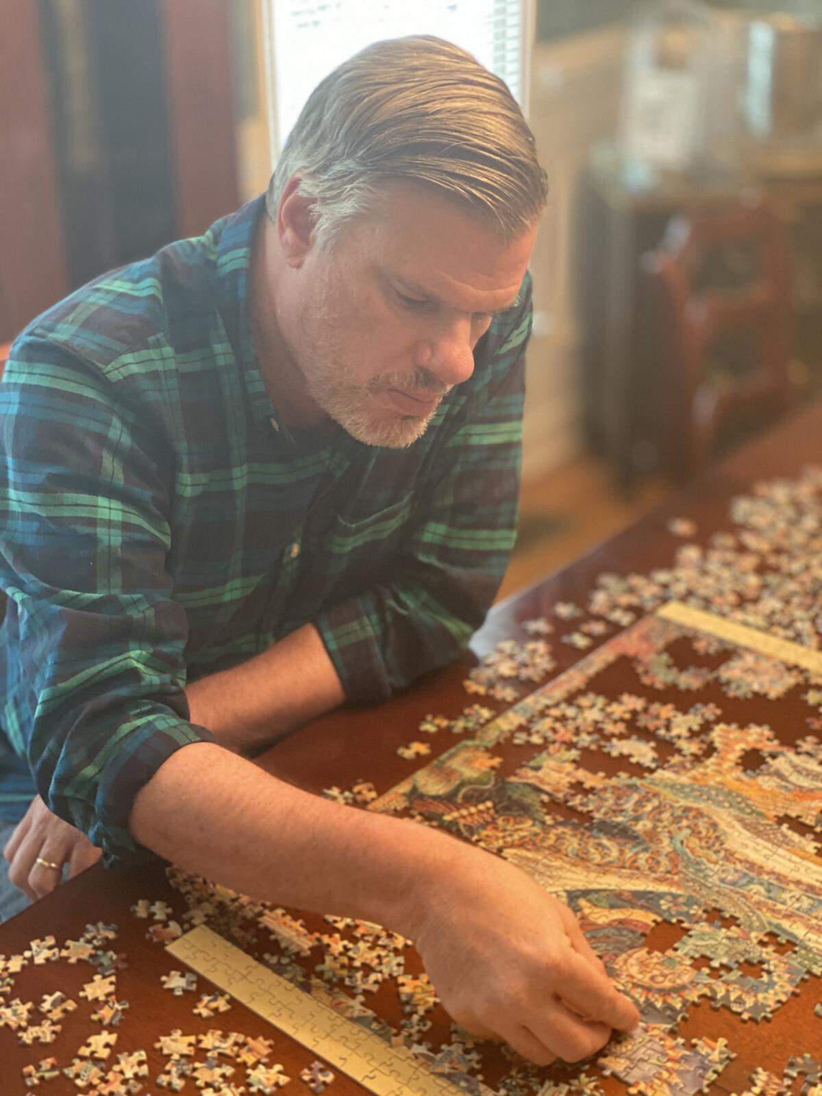 Thad Ogburn works on an art-themed puzzle. During the pandemic quarantine, he feels a connection to his late mother by working puzzles. It was a favorite hobby of hers.