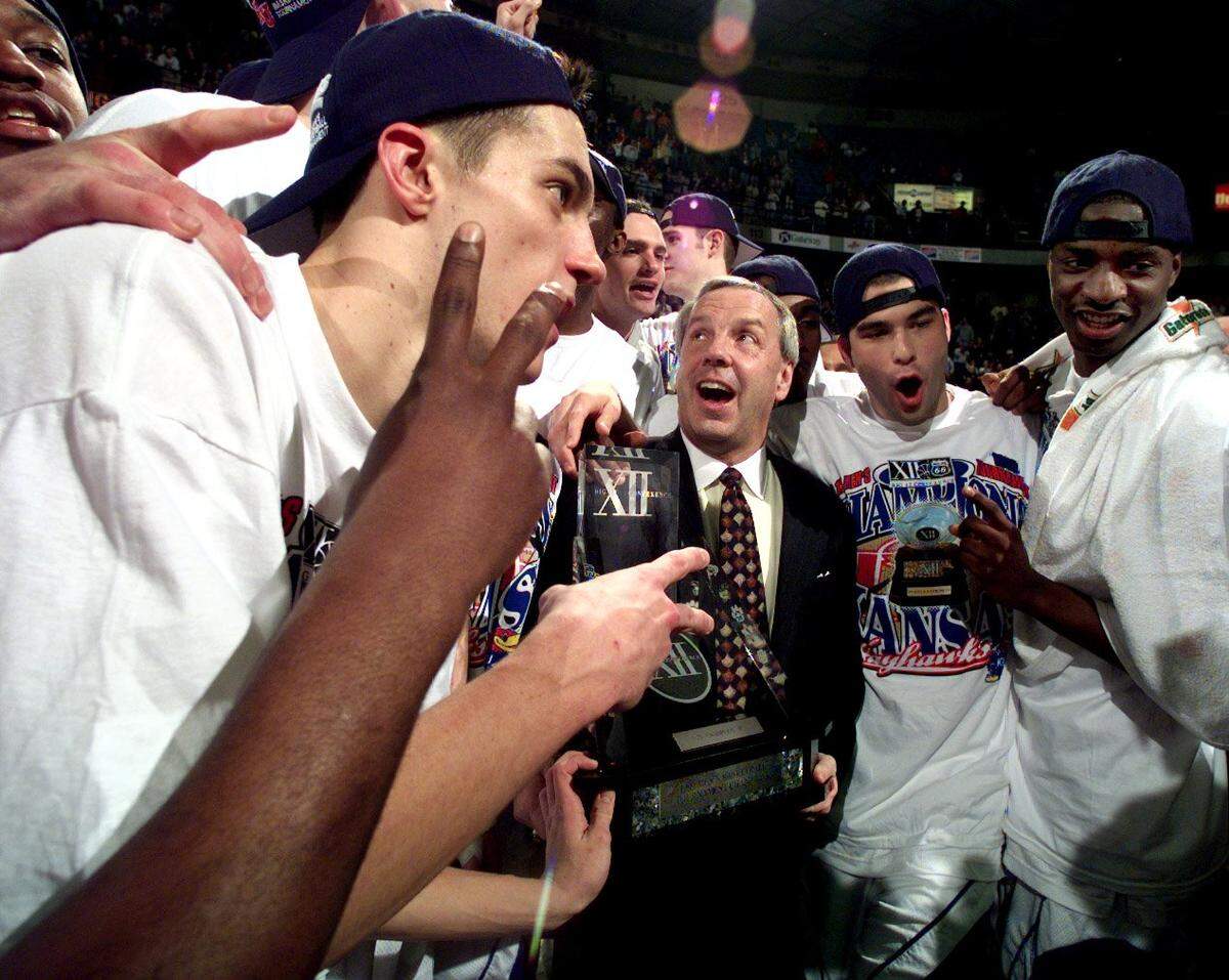 Caption: Surrounded by his players, and holding the coveted hardware, KU head coach Roy Williams celebrates the Jayhawks Big 12 Tournament Championship victory over Oklahoma State Sunday at Kemper Arena. The Jayhawks won, 53-37. photo by rich sugg/staff Photographer: RICH SUGG Credit: THE STAR Keyword: PORTRAIT Keyword: SPORT Keyword: BASKETBALL Keyword: COLLEGE