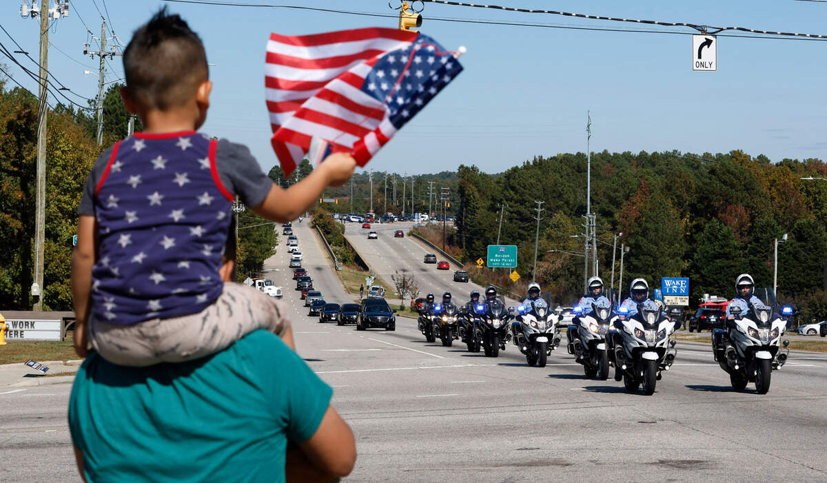 Xavier Rodriguez, 5, and his father, Oli, pay their respects as a funeral procession for Raleigh Police Officer Gabriel Torres passes them on New Bern Ave. while on its way to Brown-Wynne funeral home in Raleigh Saturday, Oct. 22, 2022. Officer Torres was killed in a mass shooting Oct. 13