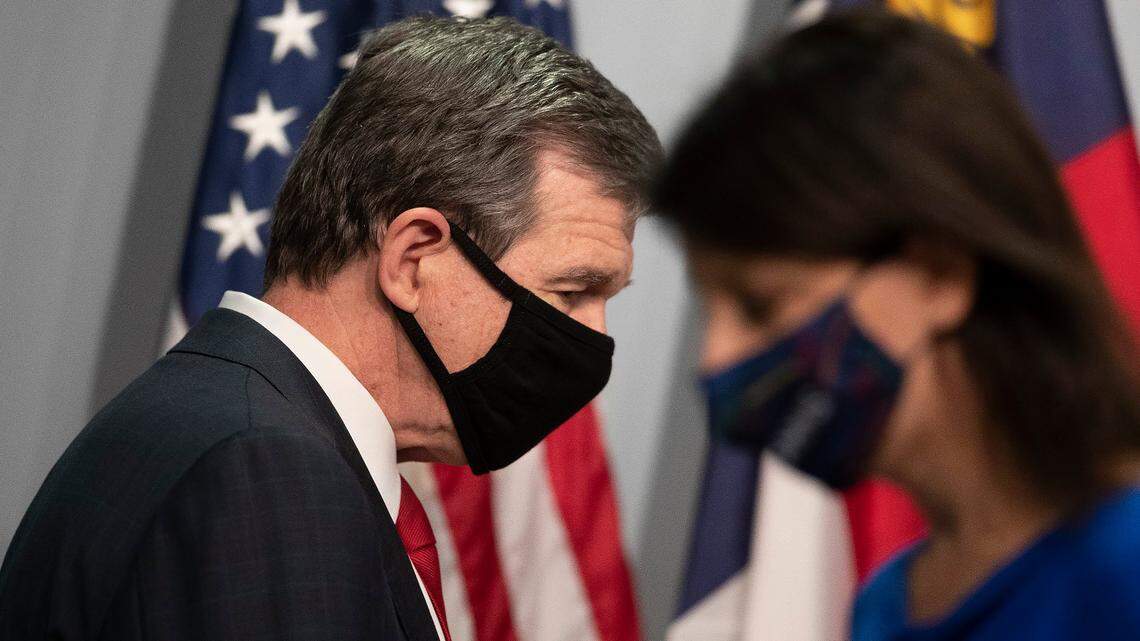 North Carolina Governor Roy Cooper and Dr. Mandy Cohen, Secretary of the North Carolina Department of Health and Human Services, trade places at the lectern during a press briefing on the COVID-19 virus and vaccine efforts on Wednesday, December 30, 2020 at the Emergency Operations Center in Raleigh, N.C.