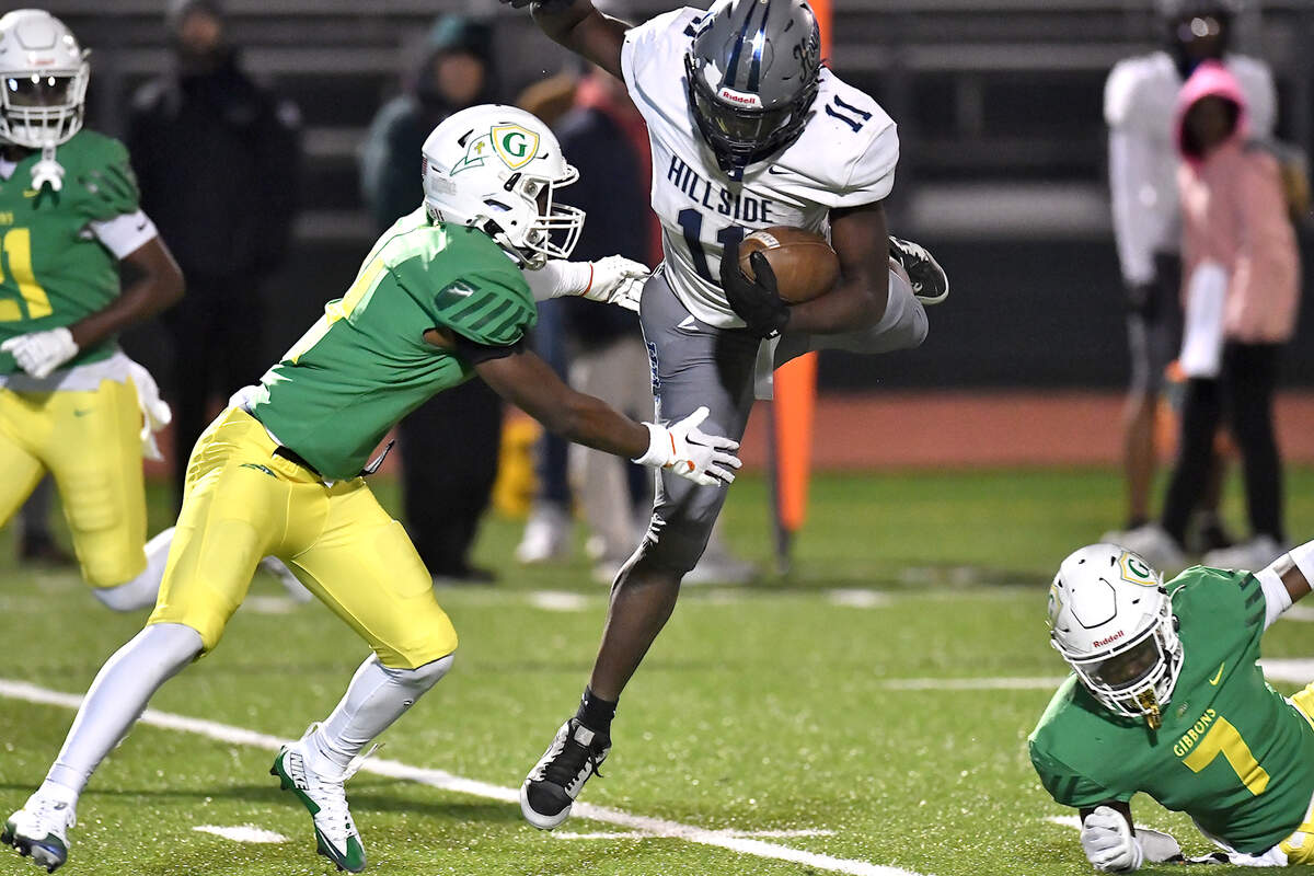 Hillside running back Ameil Braswell (11) tries to evade the tackle from Cardinal Gibbons’ Braylon Peebles (4) during the first half. The Cardinal Gibbons Crusaders and the Durham Hillside Hornets met in the third round of the NCHSAA 4A playoffs in Raleigh, N.C. on November 29, 2024.