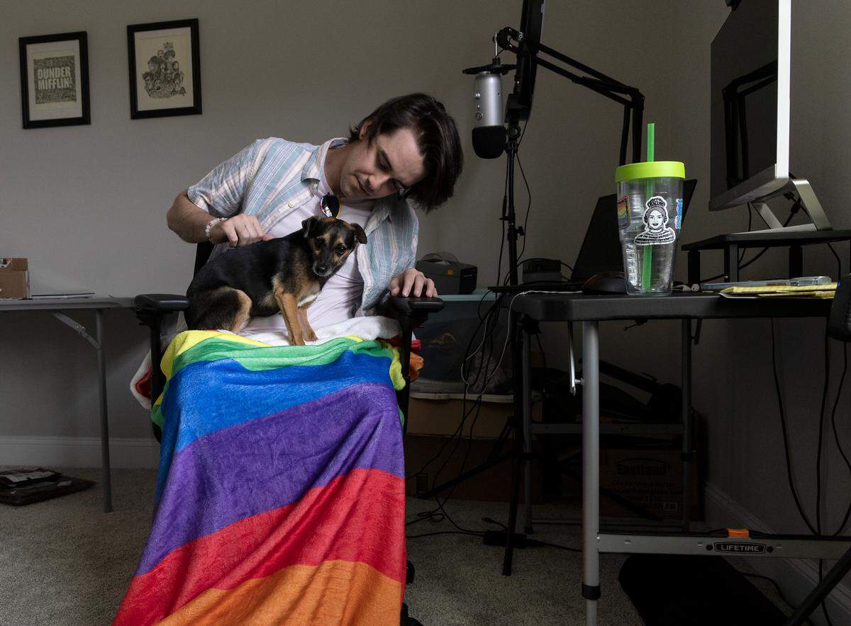 Woody Rini sits with their eight-year-old dog, Willie, at their home in Cary, N.C. on Thursday, June 29, 2023. Rini, who was assigned male at birth, now identifies as non-binary and uses they/them pronouns.