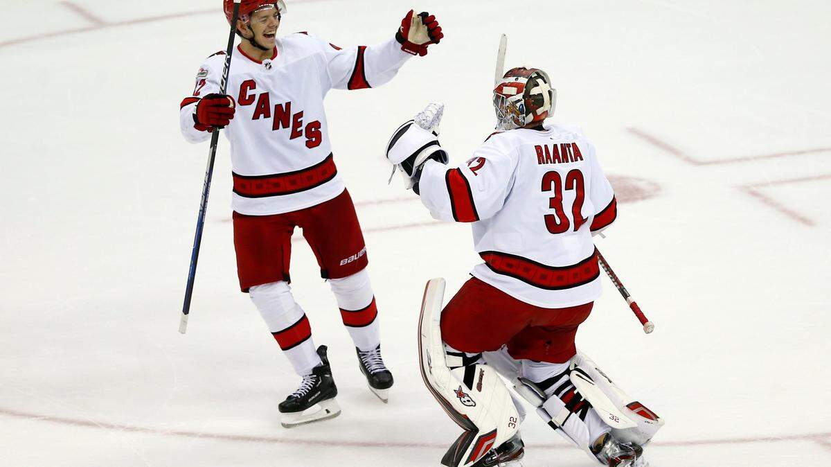Carolina Hurricanes goalie Antti Raanta (32) celebrates with teammate Jester Kotkaniemi, left, after winning in a shootout in an NHL hockey game against the New Jersey Devils, Sunday, Jan. 1, 2023, in Newark, N.J. (AP Photo/John Munson)
