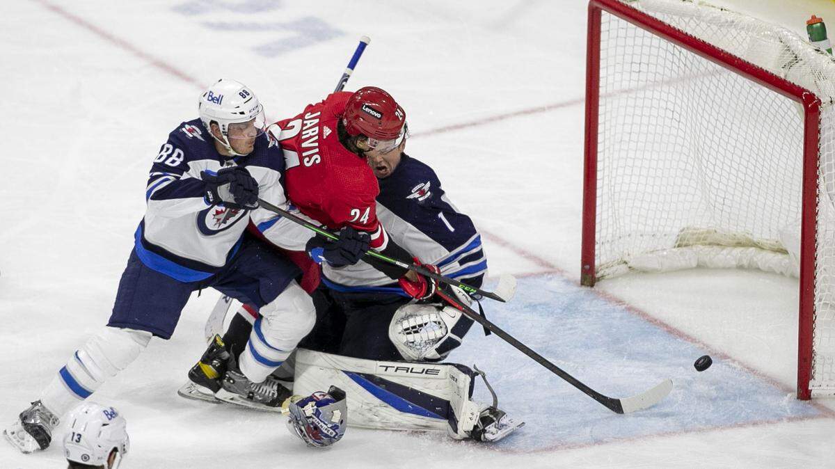 Carolina Hurricanes’ Seth Jarvis (24) scores the game winning goal on Winnipeg goalie Eric Comrie (1) in the third period on Thursday, April 21, 2022 at PNC Arena in Raleigh, N.C.