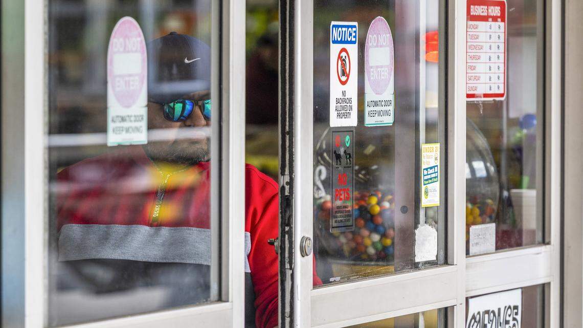 A security guard operates an automatic sliding door while watching the parking lot outside the International Foods grocery on New Hope Church Road in Raleigh on Wednesday, Nov. 19, 2025, after federal immigration enforcement agents were seen circulating the area in unmarked SUVs. Immigrant rights groups said federal agents detained at least 12 Triangle residents on Tuesday, including in Raleigh, Durham and Cary.