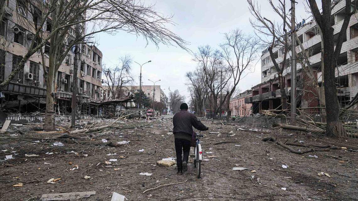A man walks with a bicycle in a street damaged by shelling in Mariupol, Ukraine, Thursday, March 10, 2022.