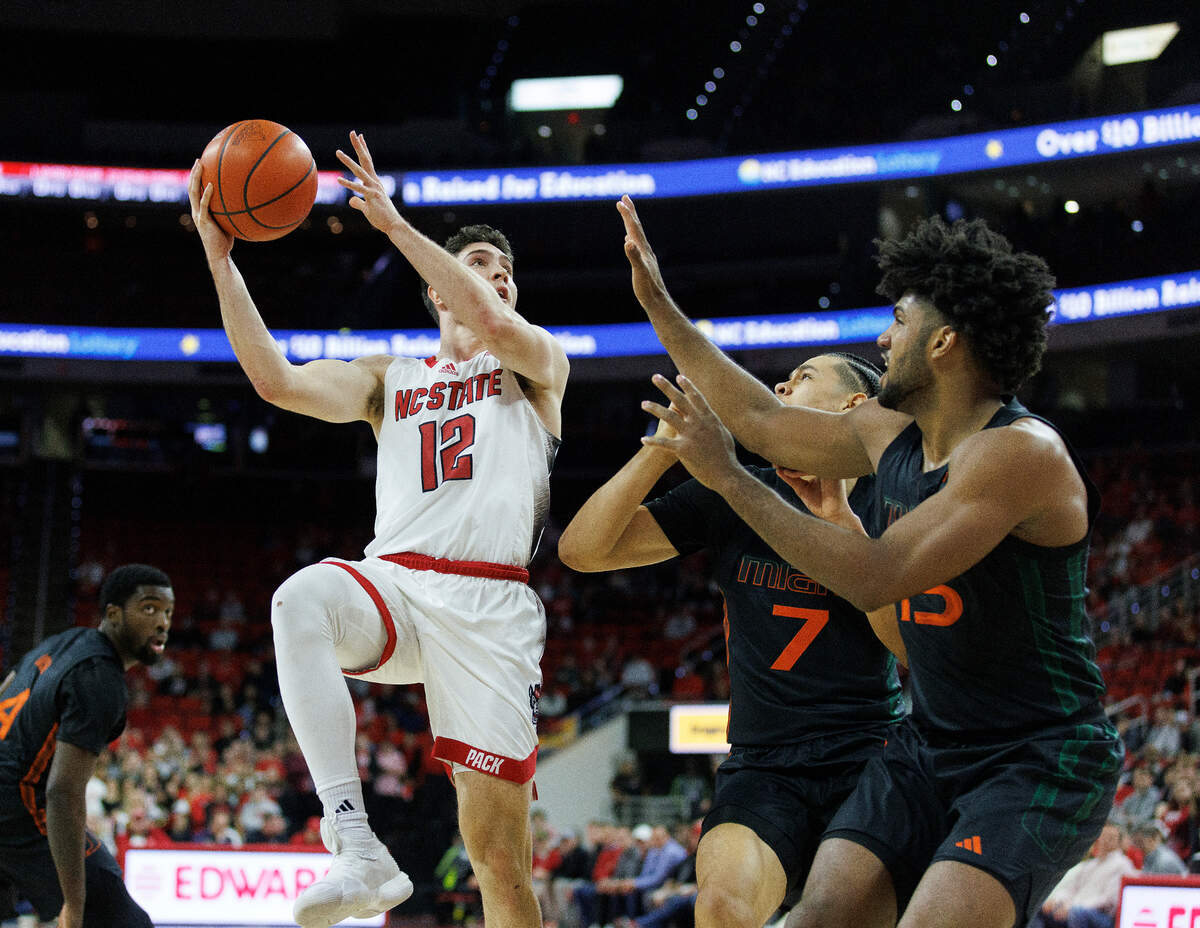 N.C. State’s Michael O’Connell shoots over Miami’s Kyshawn George and Norchad Omier during the first half of the Wolfpack’s 74-68 win on Tuesday, Jan. 30, 2024, at PNC Arena in Raleigh, N.C.