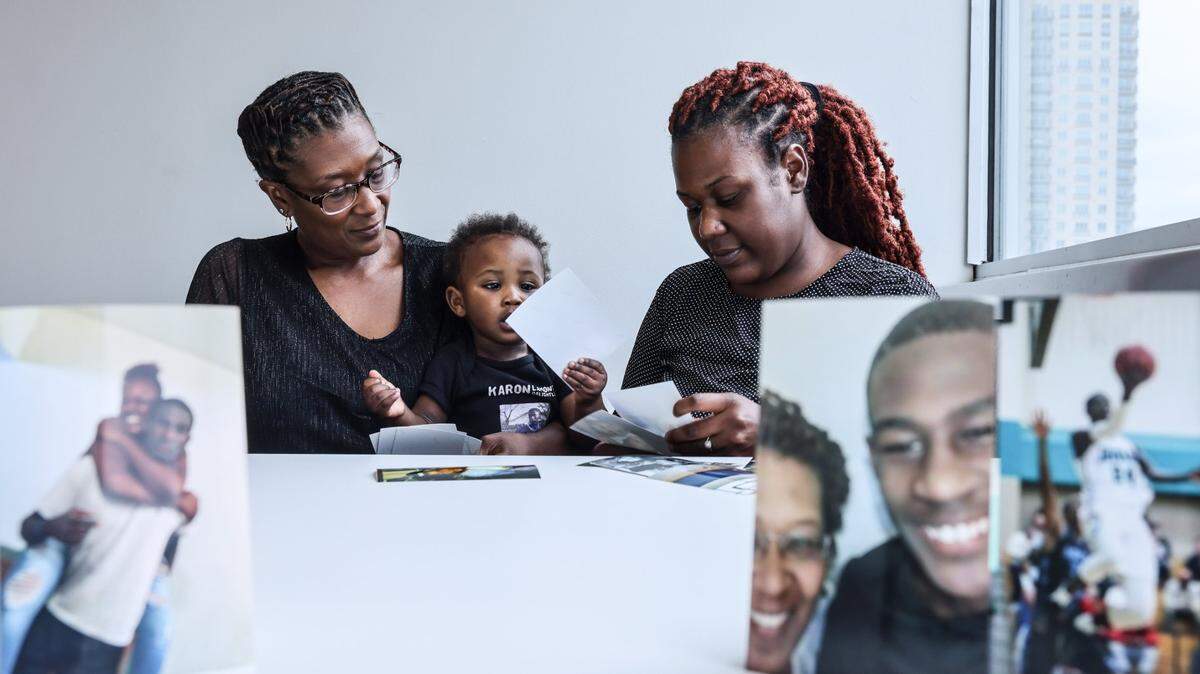 LeKisha Golightly, left, her grandson, Erick Wimbush and her daughter, Kiara Wimbush, right, look at photos of her son, Karon, who died in Mecklenburg County Jail in Charlotte on Oct. 11, 2021.