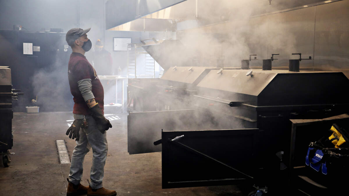 Sam Jones BBQ pit crew member Chris Wills steps back from the smoke as he works in the smokehouse in the new downtown Raleigh location on Wednesday morning, Feb. 3, 2021. The restaurant is starting off with a soft-open this week.