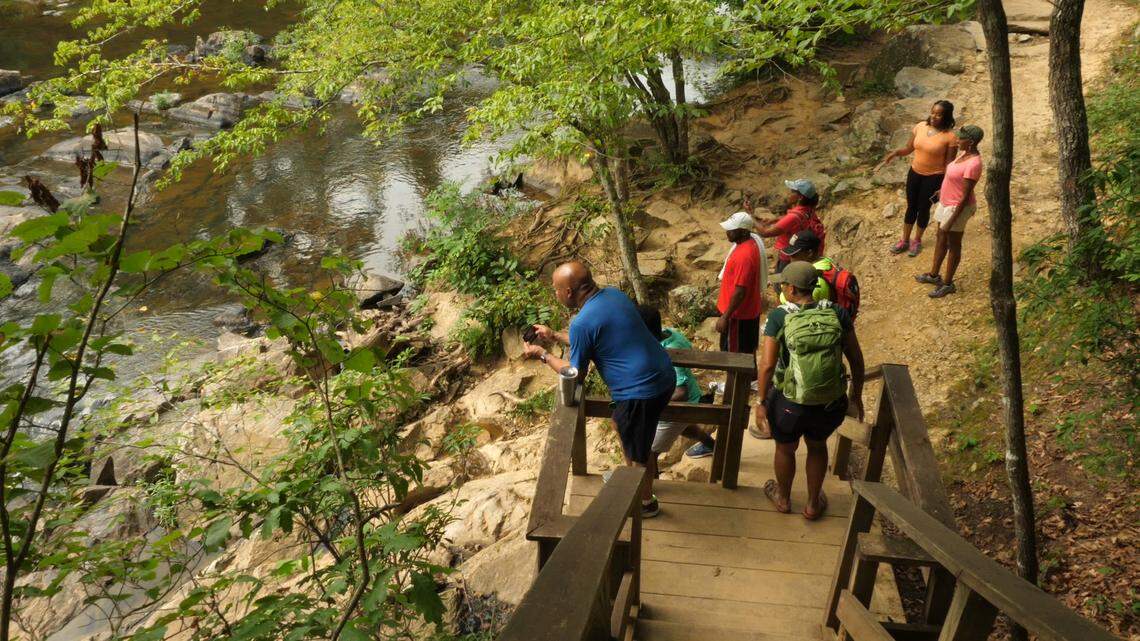Hikers take in the scenery after descending the steps during the Outdoor Afro trip to Eno River State Park
