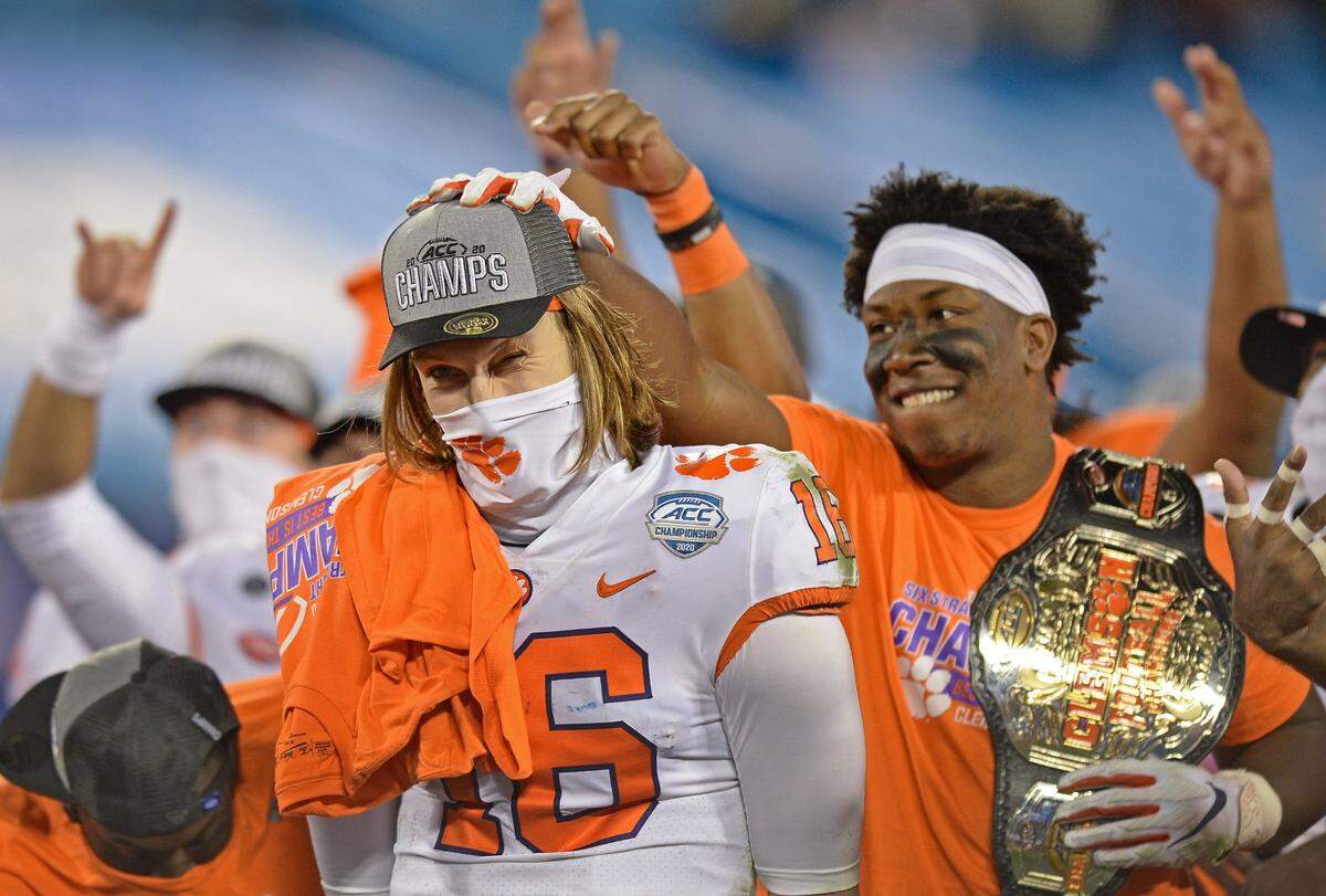 Clemson Tigers quarterback Trevor Lawrence, left, squints his left eye as a teammate pats him on the head following the ACC Championship game. Clemson defeated Notre Dame 34-10 to win the championship at Bank of America Stadium in Charlotte, NC on Saturday, December 19, 2020.  