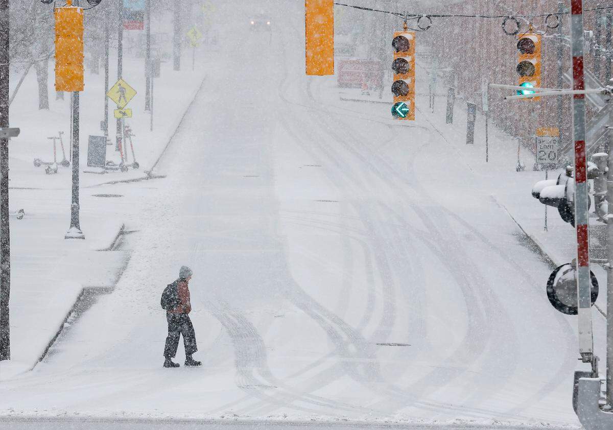A person crosses Blackwell Street as snow falls in Durham, N.C. on Wednesday, Feb. 19, 2025.