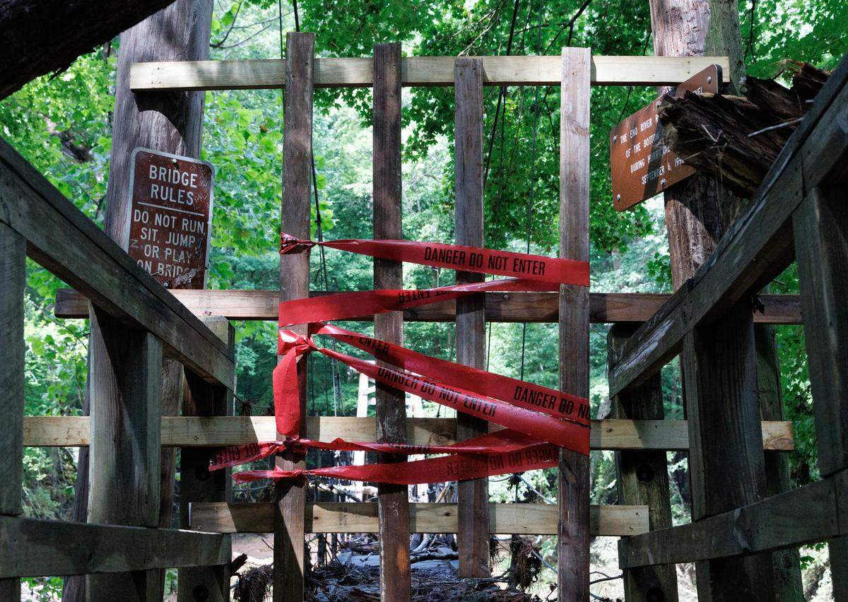 Caution tape blocks access to the swinging bridge at the Eno River State Park Fews Ford Access after it sustained damage during flooding from Tropical Depression Chantal, as pictured on Tuesday, July 15, 2025, in Durham, N.C.