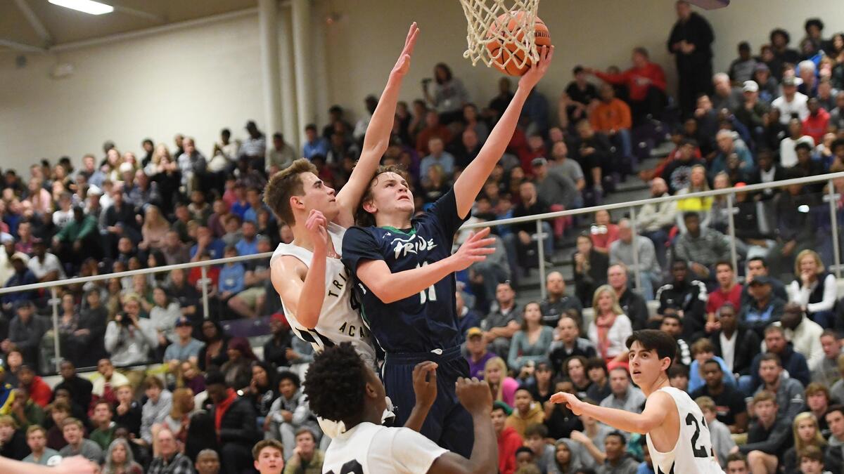 Carter Whitt (11) of Leesville Road scores with a layup against Jake Bertolini-Felice, left, and Chris Lawson (22) of Trinity Academy. The Trinity Academy Tigers played the Leesville Road Pride in high school basketball game that was part of the John Wall Holiday Invitational Tournament in Raleigh, N.C. on December 26, 2018.