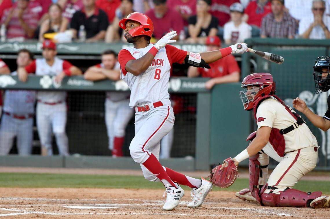 North Carolina State batter Jose Torres (8) watches the ball after connecting for a home run against Arkansas in the ninth inning during an NCAA college baseball super regional game Sunday, June 13, 2021, in Fayetteville, Ark.