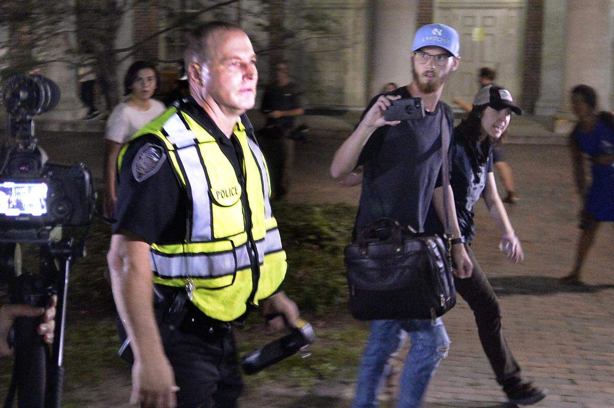 A police officer heads back to the barricaded area around the Silent Sam pedestal carrying pepper spray on the campus of UNC-Chapel Hill, Thursday, August 30, 2018.