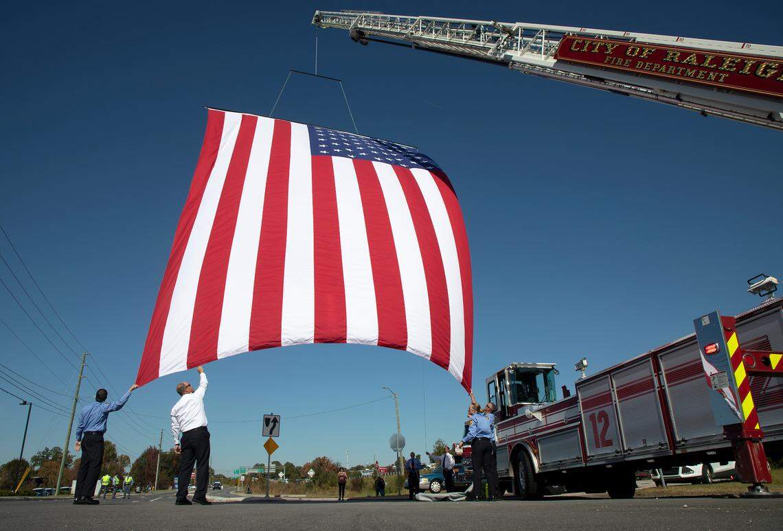 An American flag is unfurled on Yonkers Road on Saturday, Oct. 22, 2022, in Raleigh, N.C., during the funeral service for Raleigh police officer Gabriel Torres, 29, who was one of five people fatally shot near the Hedingham neighborhood on Oct. 13.