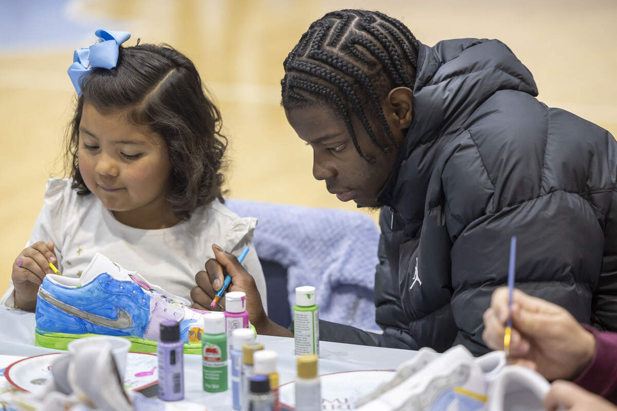 North Carolina forward Caleb Wilson paints a pair of shoes with six-year-old Sarah Ramirez of Raleigh, during a Shoes 4 Hope event on Sunday, December 14, 2025 at the Smith Center in Chapel Hill, N.C.