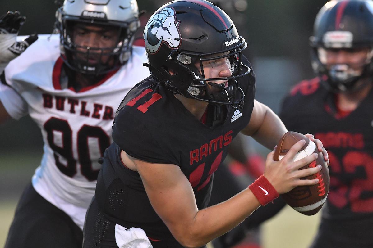 Rolesville quarterback Braden Atkinson (11) scrambles for yardage ahead of Butler’s Jadyn Farmer (90) during the first half. The Rolesville Rams and the Butler Bulldogs met in a non-conference football game in Rolesville N.C. on August 18, 2023.