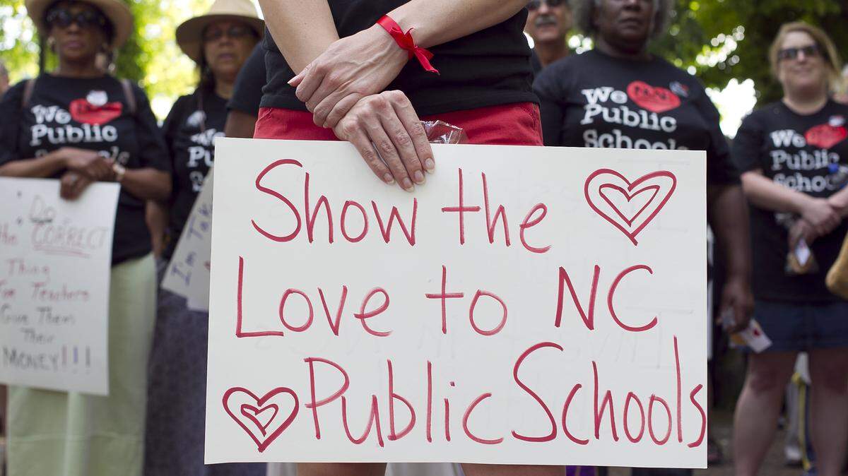 A participant at a 2014 rally in Raleigh, NC shows her support of North Carolina public schools. According to research published in February 2023, an increasing number of teachers are leaving NC public schools, and some of the state’s rural areas are experiencing the worst teacher attrition.