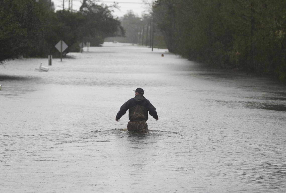 A member of the U.S. Coast Guard walks down Mill Creek Road checking houses after tropical storm Florence hit Newport N.C., Saturday, Sept. 15, 2018. 