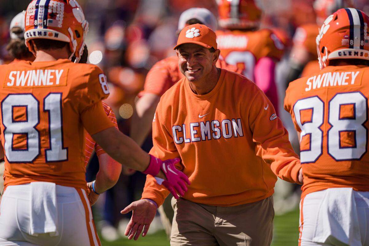 Clemson head coach Dabo Swinney smiles as he high fives wide receiver Drew Swinney (81) and wide receiver Clay Swinney (88) before an NCAA college football game against Syracuse on Saturday, Oct. 22, 2022, in Clemson, S.C.