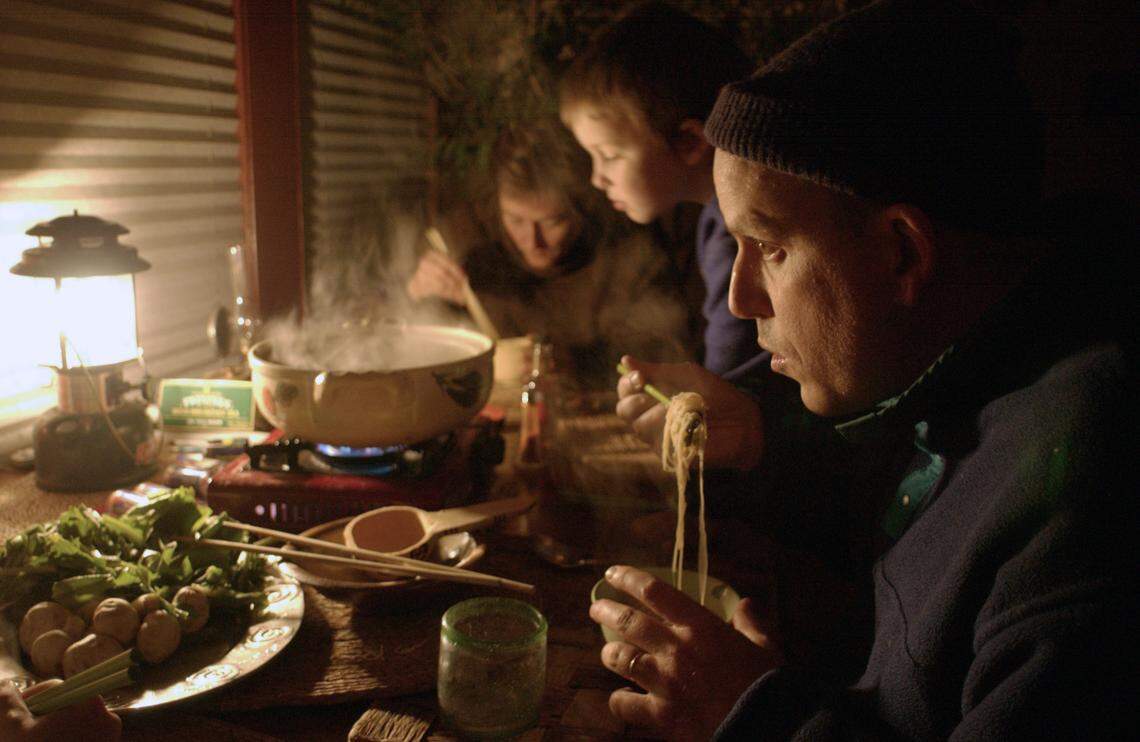 Matt Goodall’s family dines on homemade soup stewed on a camping stove as chilly darkness falls on downtown Raleigh, NC, Dec. 5, 2002. The family was waiting for power crews to repair the electrical lines to their house.  The family was housebound after the  major storm. 