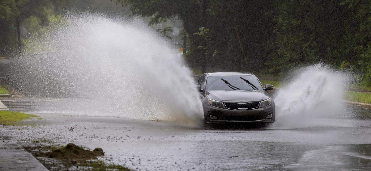 A vehicle moves through storm water that crosses State Street, flowing toward Walnut Creek, following an afternoon downpour on Wednesday, August 6, 2025 in Raleigh, N.C.