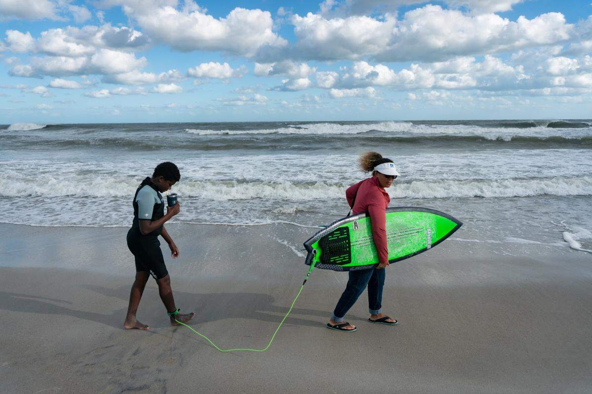 “Surfers Healing was the gateway that changed our lives,” says Heidi Ziehm, right, mother of Sterling Stewart, as they walk along Wrightsville Beach. The camp for children with autism proved to be just what her son needed.
