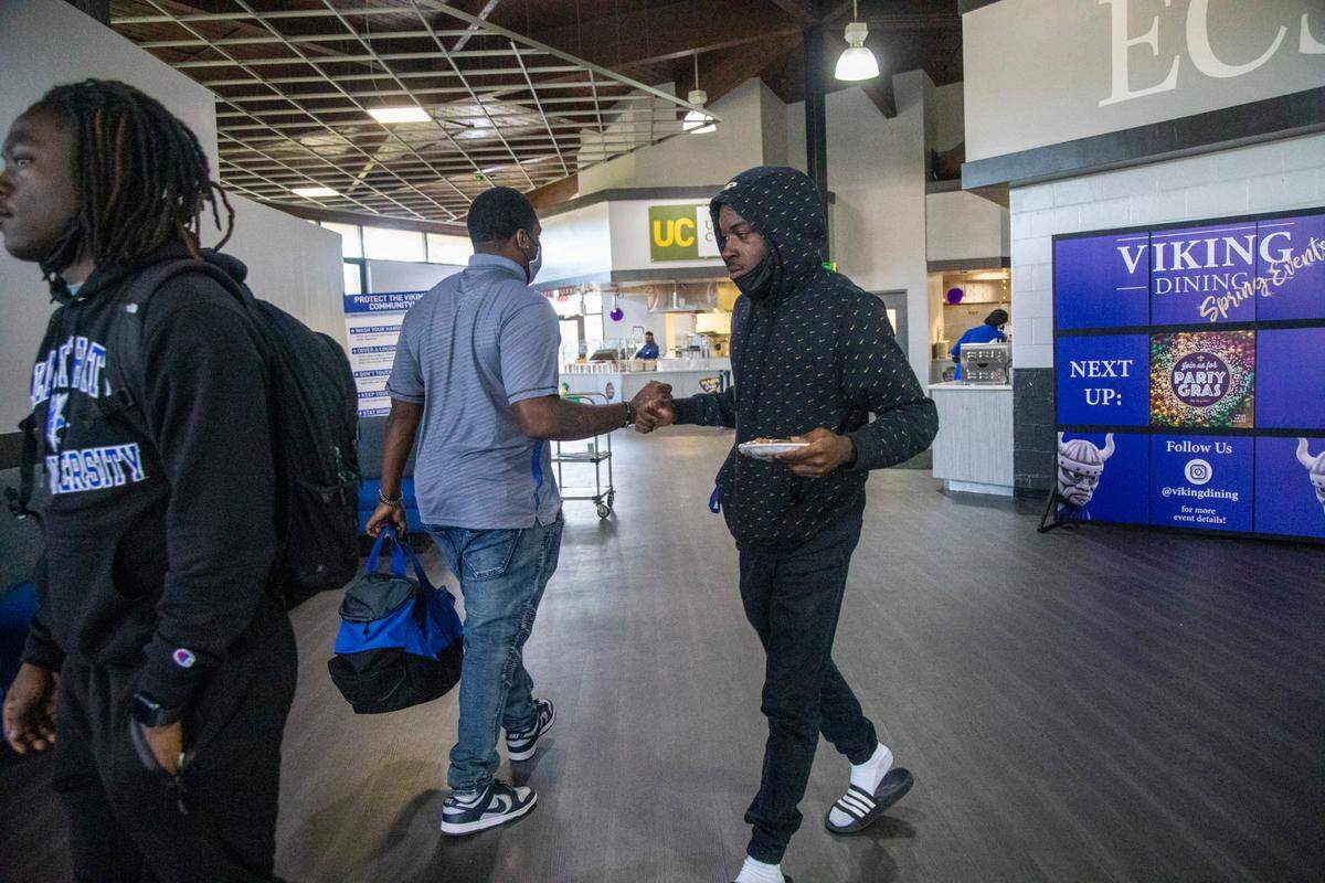 Juanya’ Majette, a senior linebacker at Elizabeth City State University, bumps fist with friends at Elizabeth City State’s Bedell Hall cafeteria Tuesday, March 1, 2022.