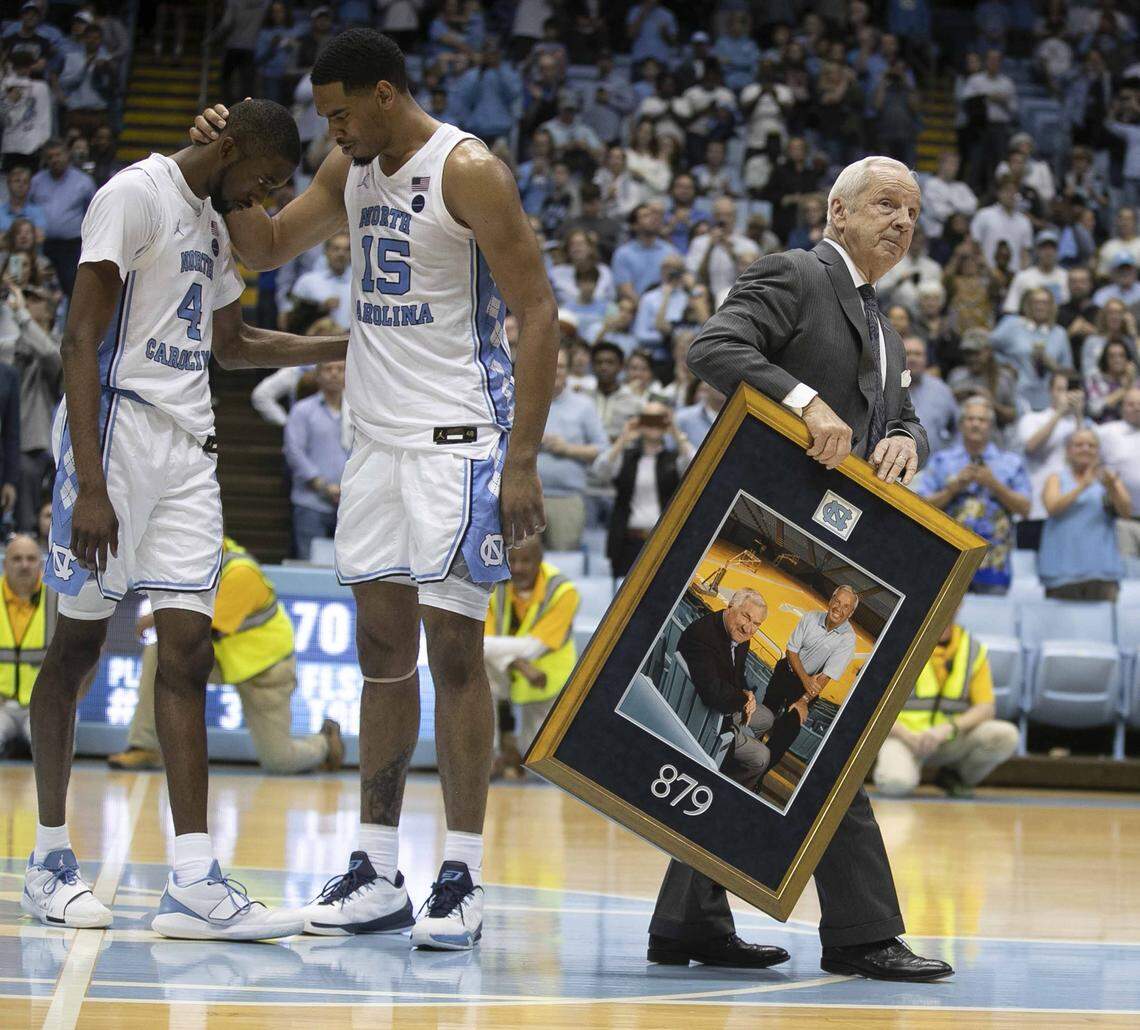 North Carolina players Brandon Robinson (4) and Garrison Brooks (15) embrace each other as coach Roy Williams leaves the court after he was honored for winning his 879th game, following the Tar Heel’s 70-67 victory over Yale on Monday, December 30, 2019 at the Smith Center in Chapel Hill, N.C.