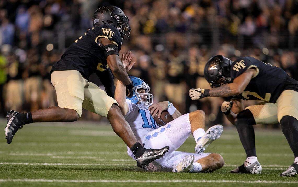 North Carolina quarterback Drake Maye (10) slides to the turf after a ten-yard gain the third quarter as Wake Forest’s Chelen Garnes (9) and J.J,Roberts (12) approach to stop him on Saturday, November 12, 2022 at Truist Field in Winston-Salem, N.C.