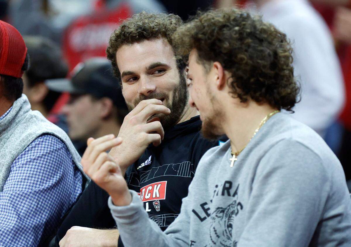 N.C. State football’s Payton Wilson, left, laughs with Thayer Thomas while watching the Wolfpack’s basketball game against William and Mary at PNC Arena on Nov. 29, 2022.