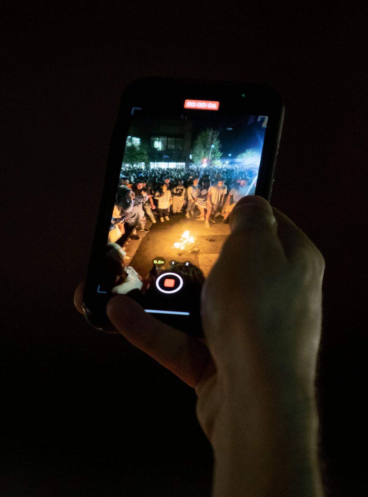 A fan records people jumping over fires on Franklin Street after UNC’s historic Final Four win against Duke on Saturday, April 2, 2022.