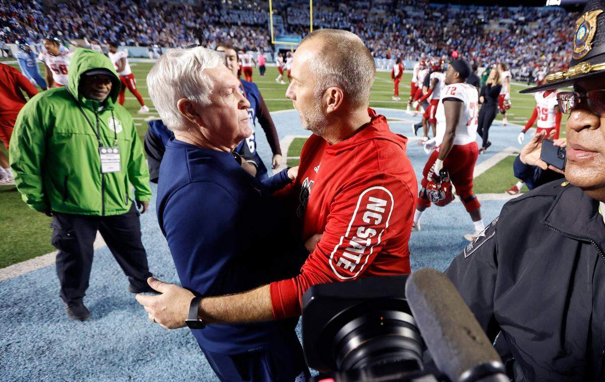 N.C. State head coach Dave Doeren talks with North Carolina head coach Mack Brown after N.C. State’s 30-27 overtime victory over UNC at Kenan Stadium in Chapel Hill, N.C., Friday, Nov. 25, 2022.