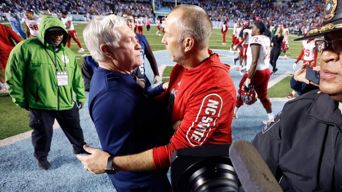 N.C. State head coach Dave Doeren talks with North Carolina head coach Mack Brown after N.C. State’s 30-27 overtime victory over UNC at Kenan Stadium in Chapel Hill, N.C., Friday, Nov. 25, 2022.