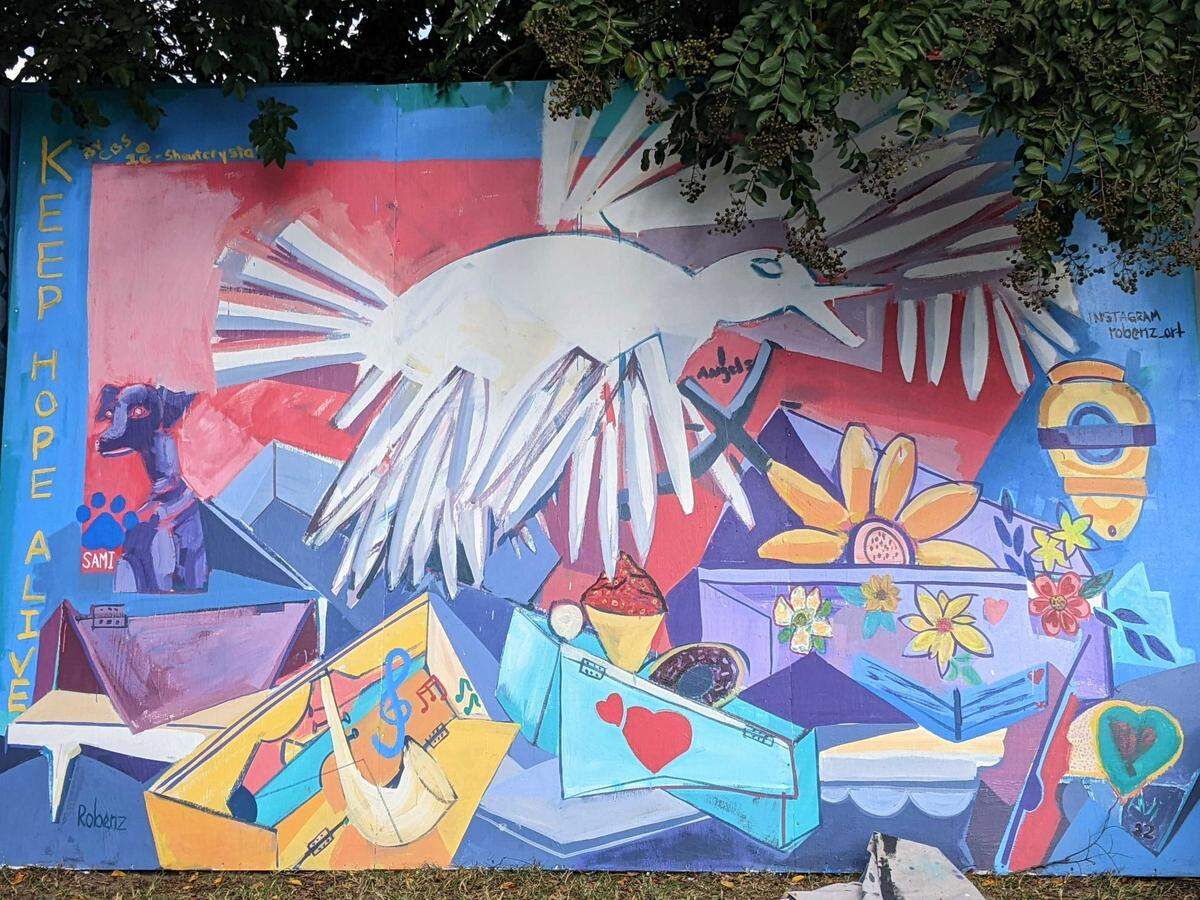 Dallas-based artist named Roberto Marquez paints a mural near the entrance of the Hedingham neighborhood in Raleigh, N.C., on Oct. 17, 2022. Marquez wanted to honor the five people killed in the mass shooting Oct. 13, 2022.